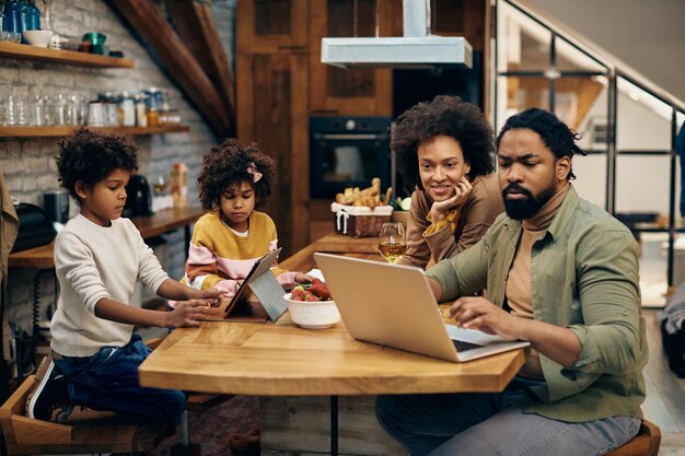 Genitori neri e figli che utilizzano la tecnologia wireless a casa