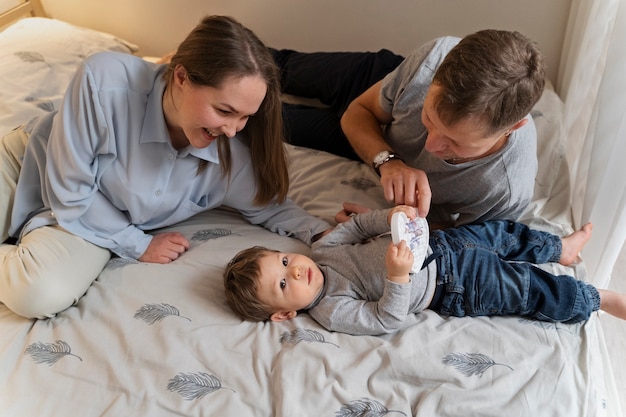 Genitori sorridenti ad alto angolo e bambino a letto