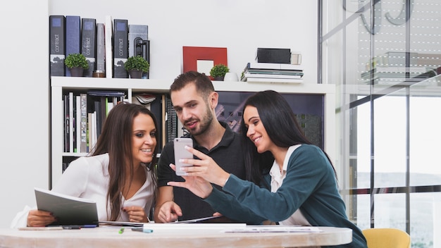 Gente allegra che guarda telefono in ufficio