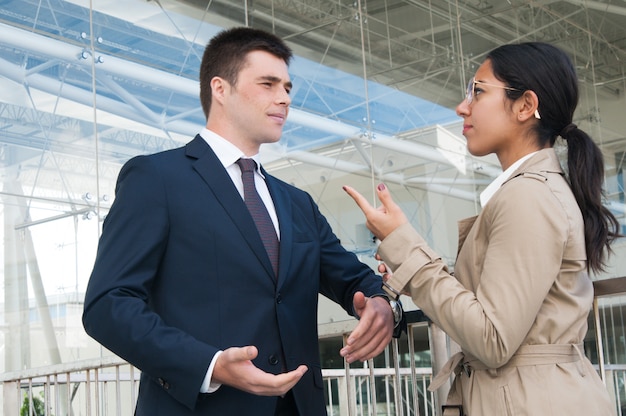 Gente di affari seria che gesturing e che discute le questioni all&#39;aperto