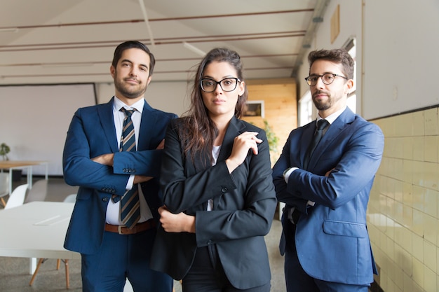 Gente di affari sicura che posa con le armi attraversate