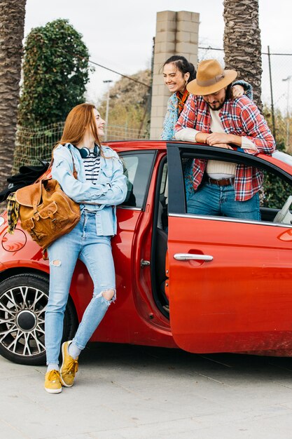 Gente felice che sta vicino all&#39;automobile rossa