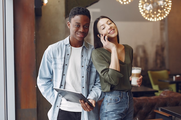 Gente internazionale in piedi in un caffè con tablet e caffè