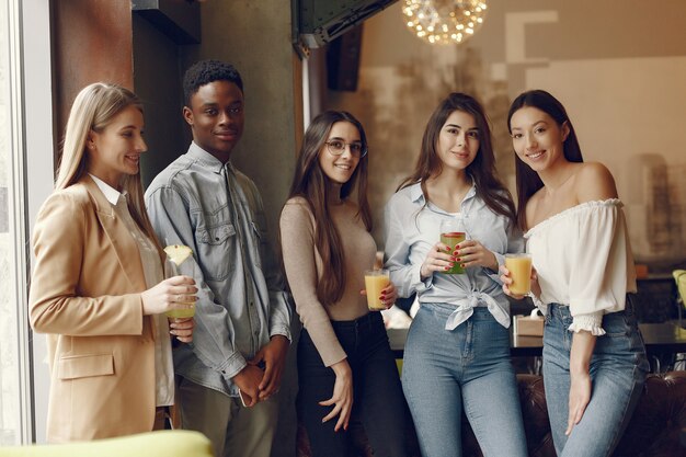 Gente internazionale in piedi in un caffè e bere un cocktail