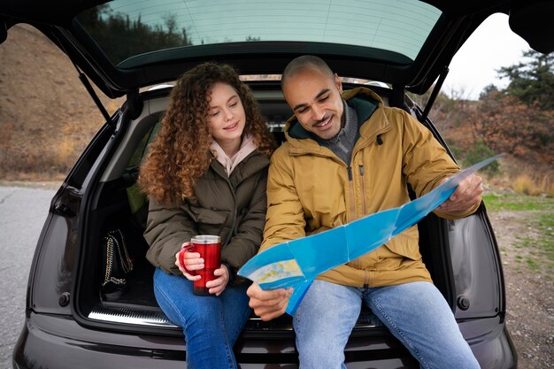 Gente sorridente di vista frontale che si siede nel bagagliaio dell'auto