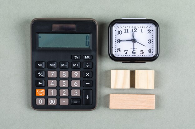 Gestione del tempo e concetto di contabilità con la lente, i blocchi di legno, il calcolatore e l'orologio sulla vista superiore del fondo grigio. immagine orizzontale