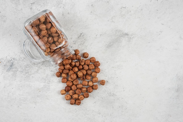 gherigli di nocciola organici dal barattolo di vetro sul tavolo di marmo.