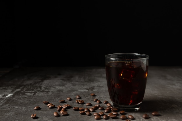 Ghiaccio caffè nero in un bicchiere sul tavolo di legno.