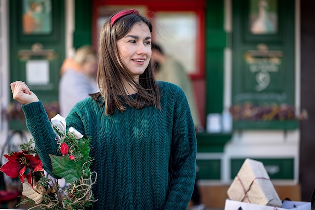 Ghirlanda di Natale nelle mani di una donna alla moda che cammina in città