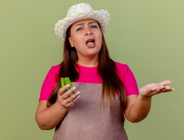 Giardiniere donna di mezza età in grembiule e cappello tenendo le metà del peperoncino verde