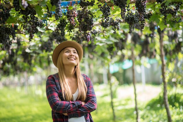 Giardiniere felice delle giovani donne che tiene i rami dell&#39;uva blu matura