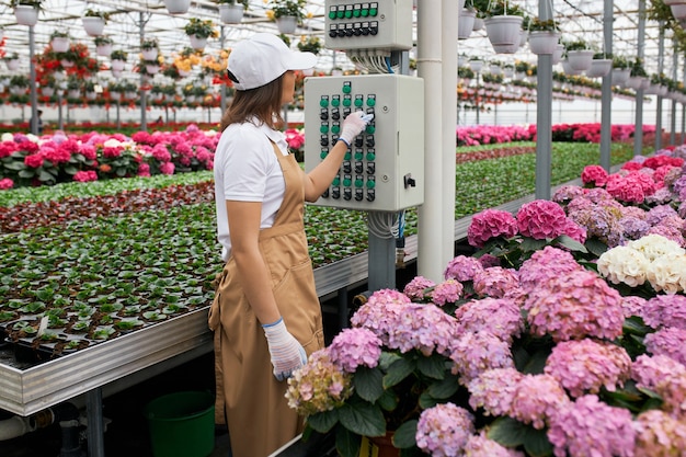 Giardiniere femminile che utilizza attrezzature moderne per innaffiare i fiori