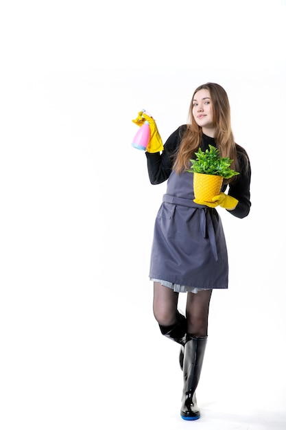 Giardiniere femminile di vista frontale in guanti gialli che innaffia la piccola pianta su bianco