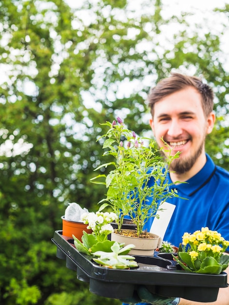 Giardiniere maschio sorridente che tiene pianta in vaso di plastica