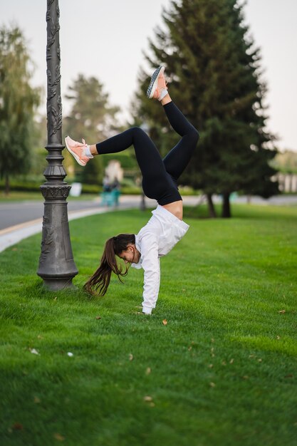 Ginnasta flessibile. Attraente donna magra che fa un backbend mentre mostra una capriola. Fuori da