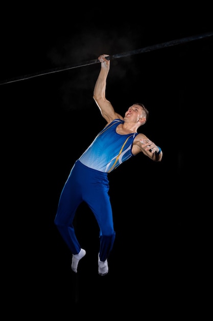 Ginnasta maschio muscolare che si allena in palestra, flessibile e attivo. Abbigliamento sportivo blu da uomo in forma caucasica