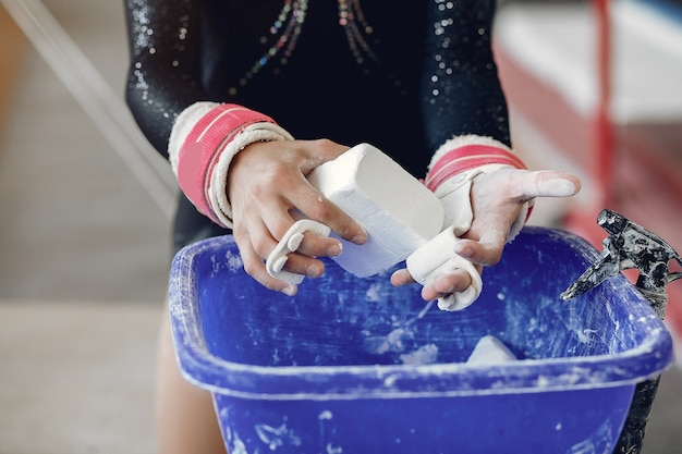 Ginnasta ragazza in impugnature di ginnastica spalmando il gesso della palestra Bambino in una scuola di atletica leggera.