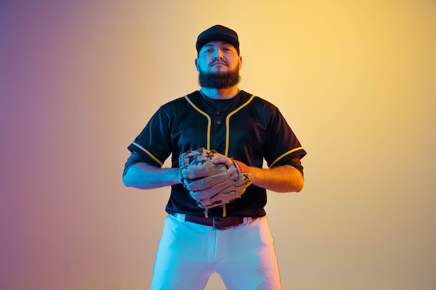 Giocatore di baseball, lanciatore in uniforme nera che si esercita e si allena su sfondo sfumato alla luce al neon