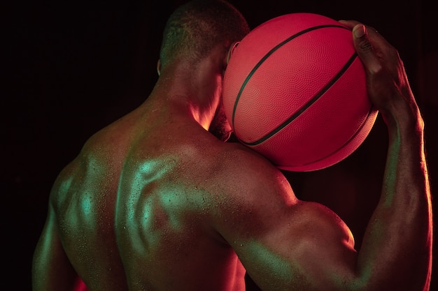 Giocatore di basket giovane muscoloso afro-americano in azione di allenamento di gioco