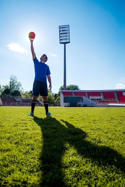 Giocatore di calcio sollevando palla con la mano