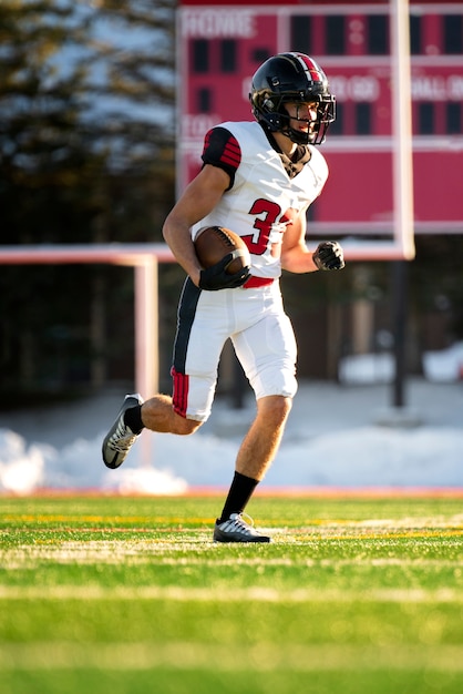 Giocatore di football americano maschio in formazione uniforme sul campo