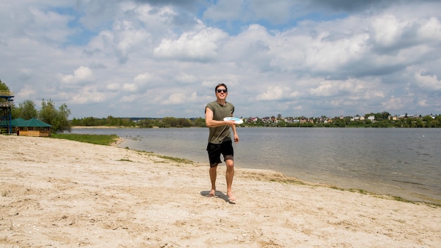 Giocatore di frisbee maschio sulla spiaggia sabbiosa