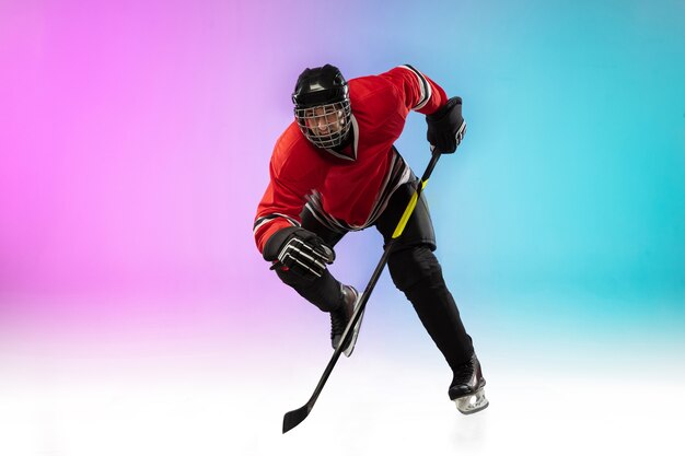 Giocatore di hockey maschio con il bastone sul campo da ghiaccio e lo spazio sfumato al neon