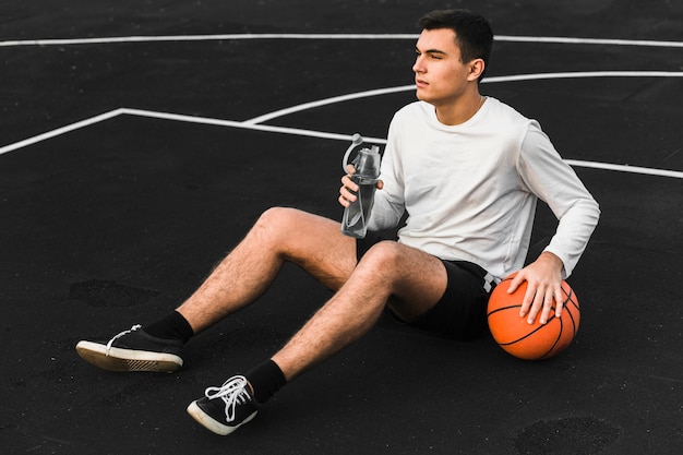 Giocatore di pallacanestro che tiene bottiglia di acqua