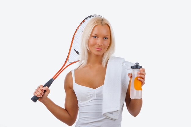 Giocatore di tennis femminile biondo positivo in un vestito bianco.