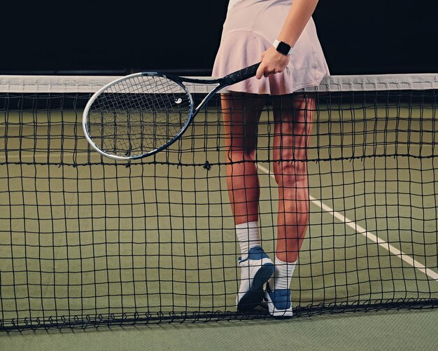 Giocatore di tennis femminile sexy che posa su un campo da tennis. Vista posteriore, glutei.