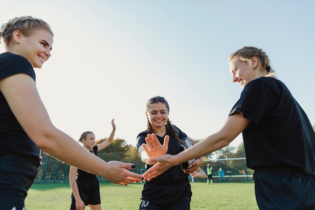 Giocatori di rugby femminile che uniscono le mani