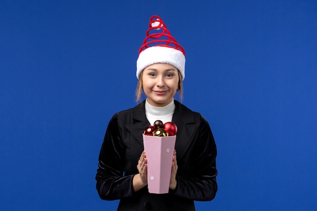 Giocattoli abbastanza femminili dell'albero di Natale della tenuta di vista frontale sul nuovo anno blu di festa della parete blu