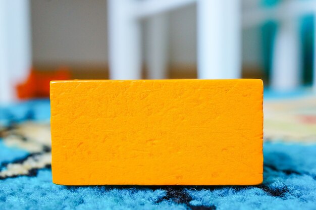 Giocattolo rettangolare arancione per bambini posto su una superficie multicolore
