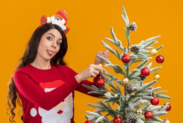 Giocosa giovane bella ragazza che indossa la fascia e il maglione di Babbo Natale