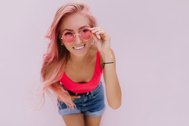 Gioiosa donna caucasica con i capelli rosa in posa con un sorriso carino.