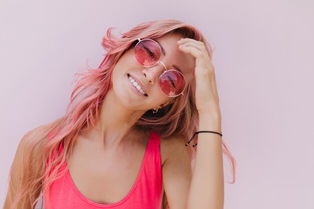 Gioiosa donna caucasica con i capelli rosa in posa con un sorriso carino.