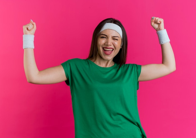 Gioiosa giovane donna sportiva che indossa fascia e braccialetti cercando ammiccanti facendo gesto di sì