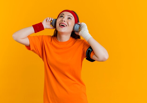 Gioiosa giovane donna sportiva che indossa la fascia e braccialetti e cuffie