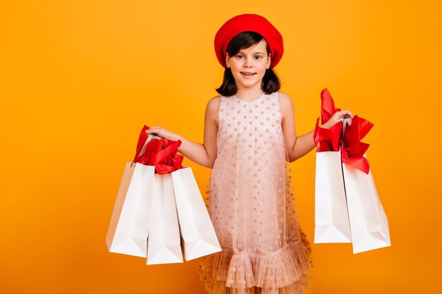 Gioioso bambino francese in posa dopo lo shopping. ragazzo sorridente con sacchetti di carta.