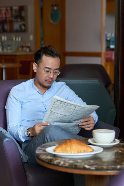 Giornale della lettura dell'uomo d'affari in coffeshop