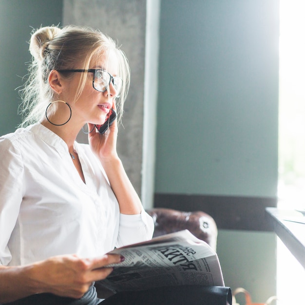 Giornale della tenuta della donna di affari che parla sul cellulare