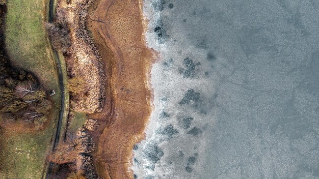 Giornata di sole della fotografia del drone dall'alto verso il basso della riva del lago ghiacciato