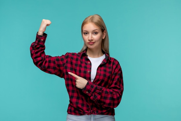 Giornata internazionale degli studenti forte giovane ragazza carina in camicia rossa a quadri che mostra i bicipiti