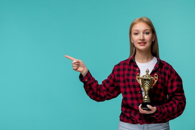 Giornata internazionale degli studenti ragazza carina in camicia rossa a quadri che punta a sinistra e tiene in mano un trofeo