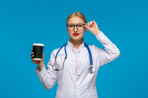 Giornata mondiale dei medici medico serio che tiene la tazza di caffè con lo stetoscopio nel camice medico