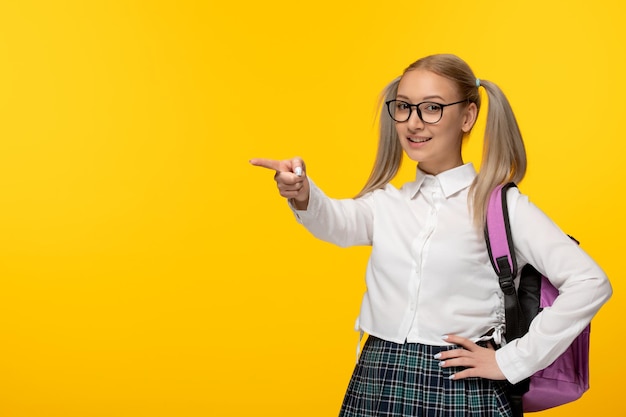 Giornata mondiale del libro divertente studentessa felice che punta il dito in uniforme scolastica