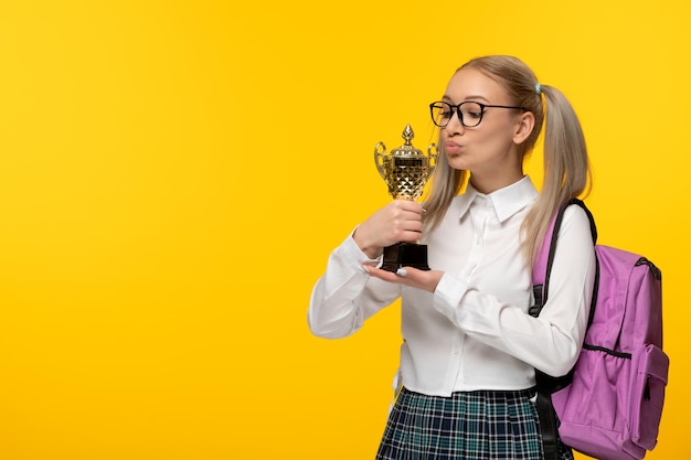 Giornata mondiale del libro una scolaretta bionda carina in uniforme che bacia un trofeo d'oro