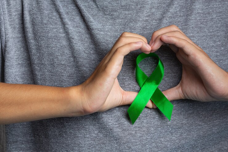 Foto gratuito giornata mondiale della salute mentale. mano d'uomo che mostra a forma di cuore intorno a un nastro verde