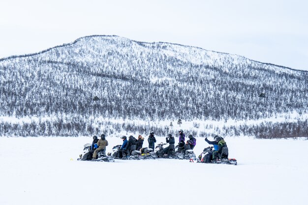 Giornata nevosa con persone che guidano le motoslitte e una montagna in lontananza nel nord della Svezia