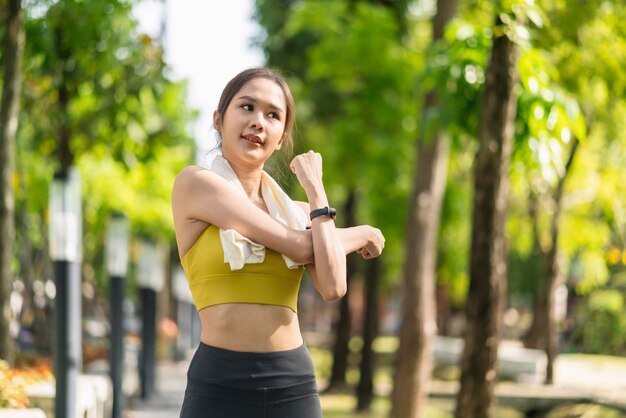 Giovane adulto asiatico allegro Attraente e forte stretching mattutino prima di correre nel parco Concetto di sport Stile di vita sano Giovane corridore di fitness donna che si allunga prima di correre sul parco